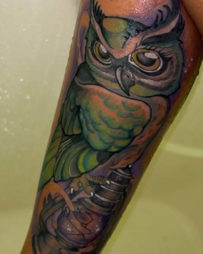 Color tattoo of an owl in green, orange and purple tones perched on a forearm.